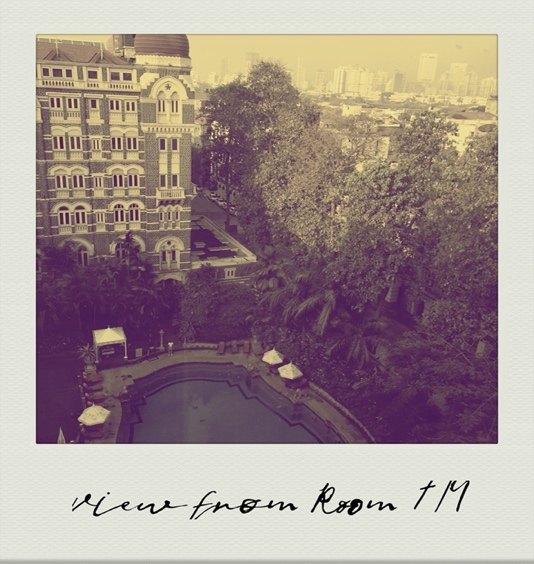 Photograph: the view from a Mumbai hotel room — a courtyard pool and old stone buildings.